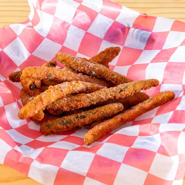 Fried churro-like sticks, dusted with sugar, served in a red and white checkered paper basket.